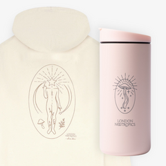White Find Your Flow zip hoodie pictured from behind next to a blush pink MiiR travel cup, featuring London Nootropics Mushroom designs, on a white background.
