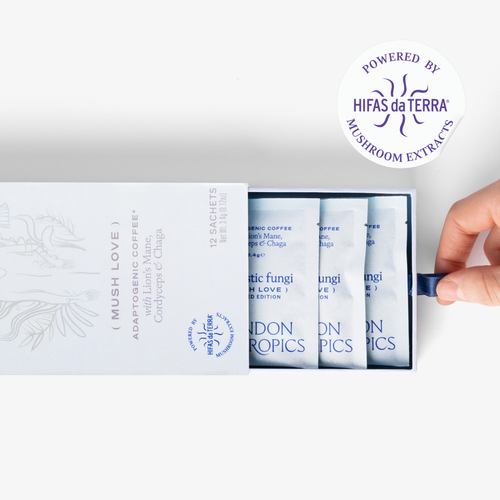 Slightly opened box of Mush Love Lion's Mane, Cordyceps, and Chaga adaptogenic coffee showing three single serve sachets. A hand pull the box open. In the top right corner is a sticker that reads: Powered by Hifas da Terra mushroom extracts.