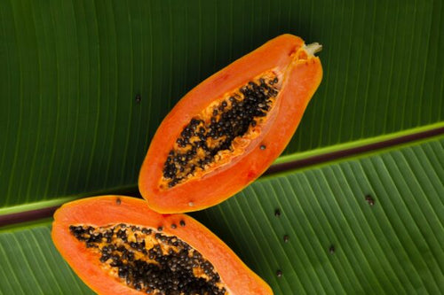 Papaya cut lengthwise with the flesh and seeds exposed, sitting atop a banana leaf. Featured image for blog post about ashwagandha and libido.