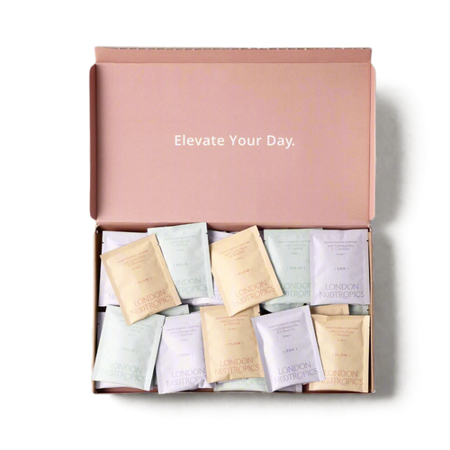 Open box of London Nootropics adaptogenic coffee sachets, neatly arranged in pastel-coloured packaging. The inside lid of the box features the phrase "Elevate Your Day." in white text on a muted pink background.